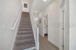 stairs with baseboards, wood finished floors, and recessed lighting