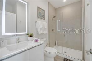 bathroom featuring toilet, a shower stall, and vanity