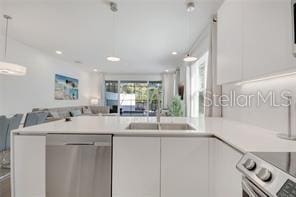 kitchen featuring stainless steel appliances, a sink, white cabinets, open floor plan, and light countertops