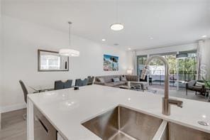 kitchen featuring recessed lighting, a sink, open floor plan, light countertops, and pendant lighting