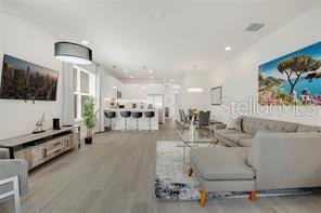 living room featuring wood finished floors, visible vents, and recessed lighting