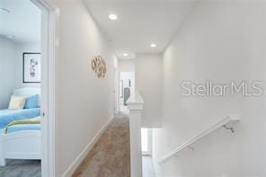 hallway with recessed lighting, baseboards, and an upstairs landing