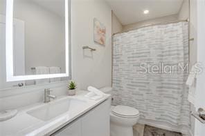 full bath with toilet, shower / bath combo with shower curtain, and vanity