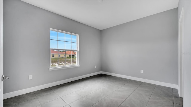 tiled spare room featuring baseboards