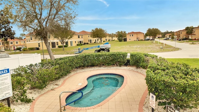 view of swimming pool with a residential view, a lawn, and fence