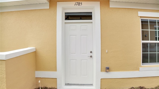 doorway to property featuring stucco siding