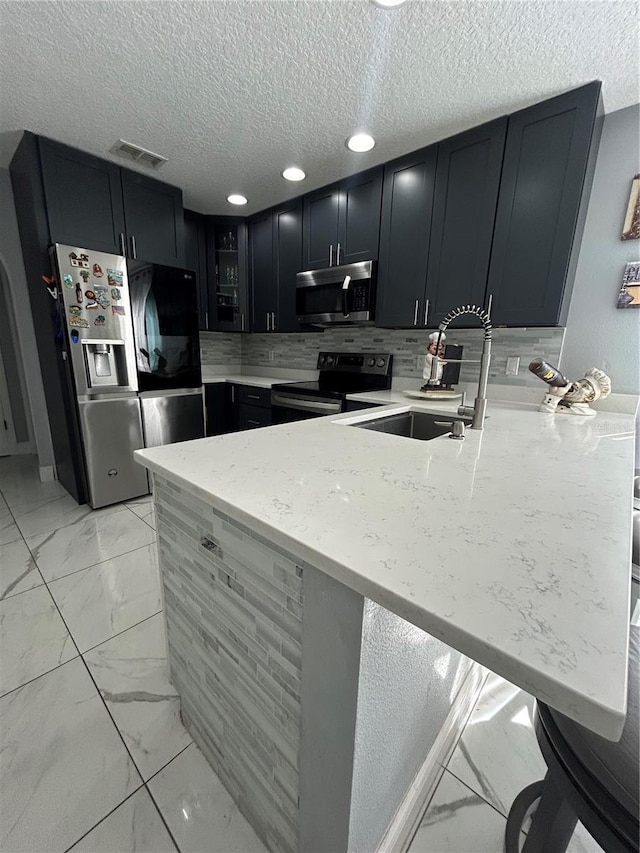 kitchen featuring marble finish floor, visible vents, appliances with stainless steel finishes, a sink, and a peninsula