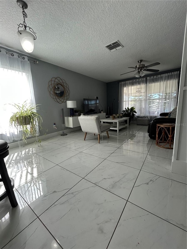 unfurnished dining area featuring a textured ceiling, marble finish floor, ceiling fan, and visible vents