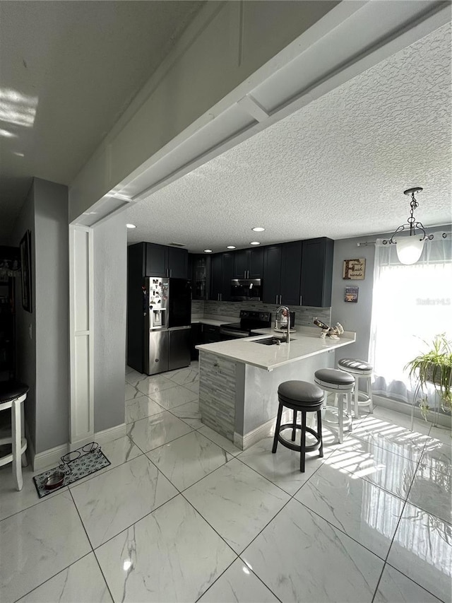 kitchen featuring marble finish floor, appliances with stainless steel finishes, a sink, dark cabinets, and a kitchen breakfast bar