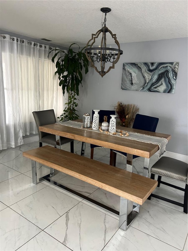 dining space with marble finish floor, a notable chandelier, a textured ceiling, and baseboards