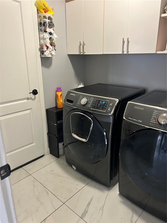 washroom featuring cabinet space, marble finish floor, and separate washer and dryer