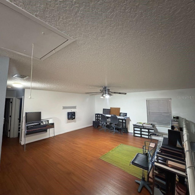 home office featuring attic access, baseboards, a ceiling fan, wood finished floors, and a textured ceiling