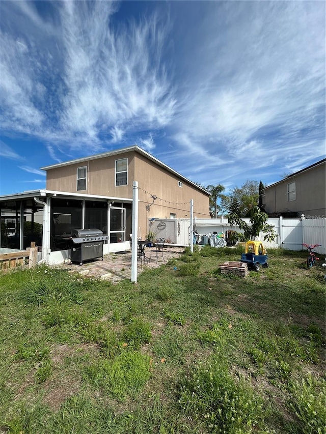 rear view of property with a sunroom, fence, and a lawn