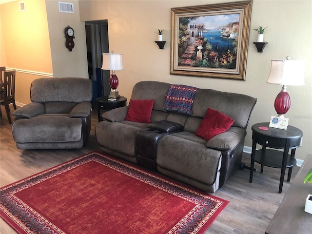 living area with visible vents, baseboards, and wood finished floors