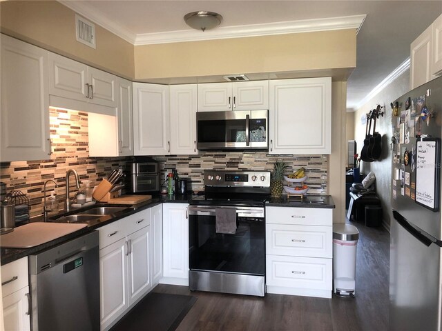 kitchen with stainless steel appliances, visible vents, ornamental molding, white cabinets, and a sink