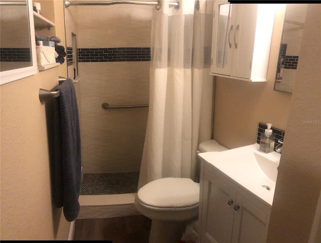 bathroom with toilet, a stall shower, and vanity