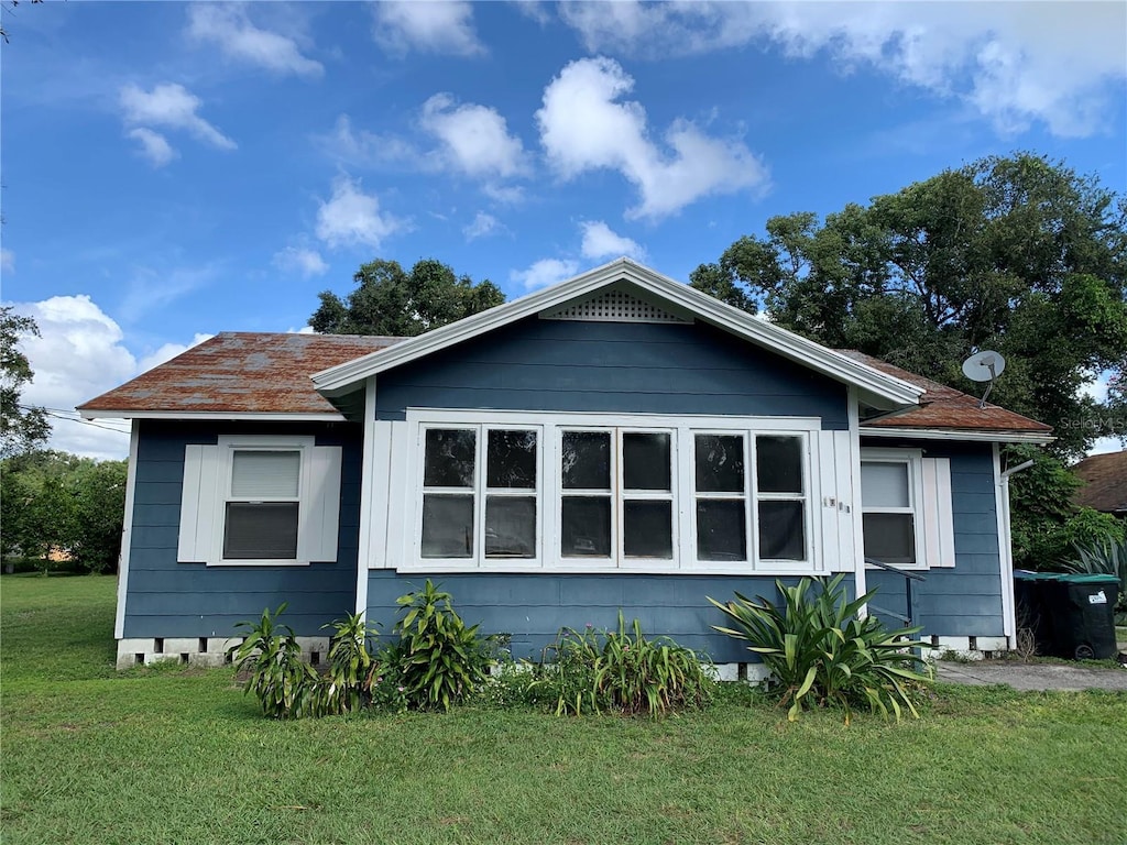 exterior space featuring a lawn and a shingled roof