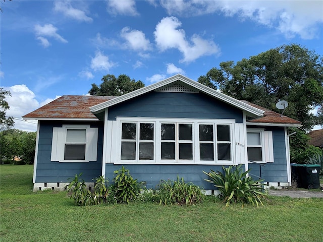 exterior space featuring a lawn and a shingled roof