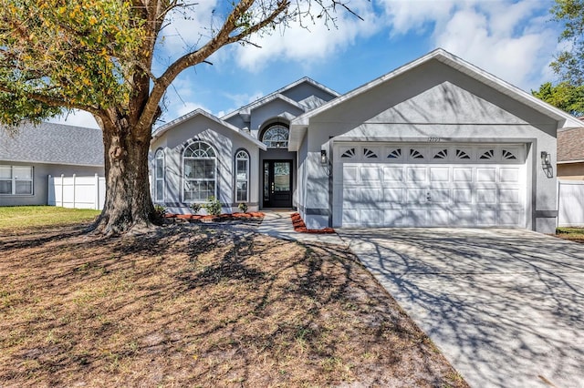 single story home featuring a garage, fence, driveway, and stucco siding