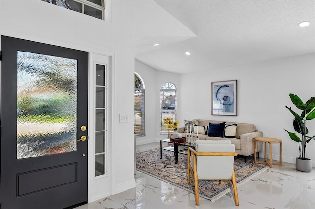 entryway with recessed lighting, marble finish floor, a textured ceiling, and baseboards