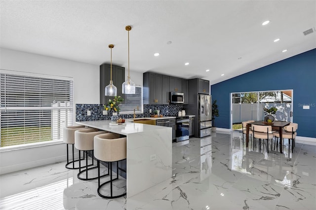 kitchen with marble finish floor, a breakfast bar area, tasteful backsplash, appliances with stainless steel finishes, and a sink