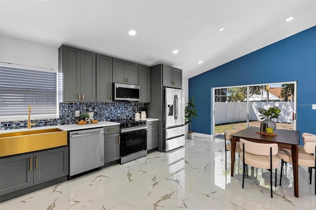 kitchen featuring stainless steel appliances, a sink, marble finish floor, light countertops, and decorative backsplash