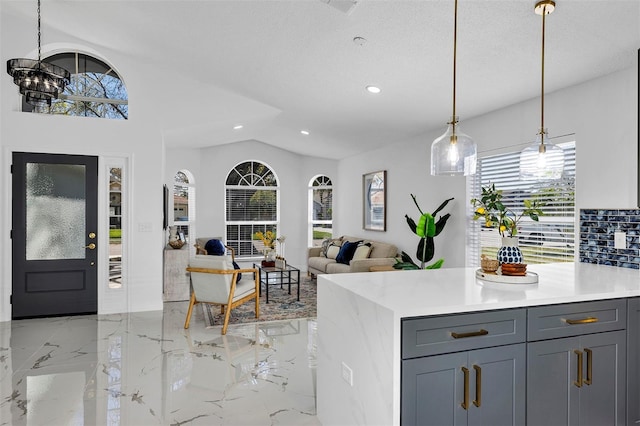 kitchen featuring lofted ceiling, marble finish floor, hanging light fixtures, and light countertops