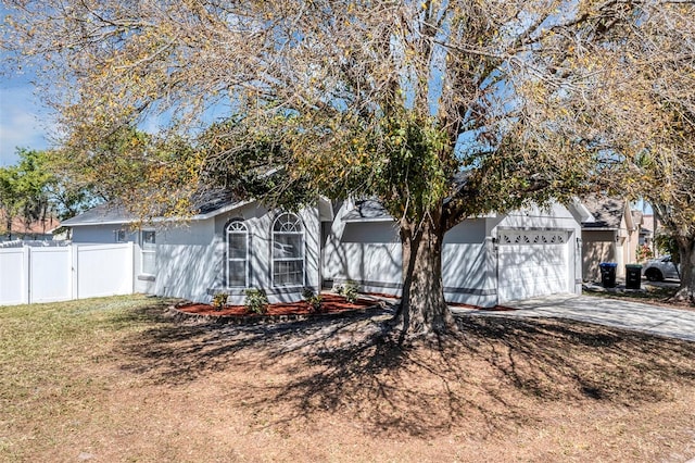 view of front of home featuring a front yard, driveway, an attached garage, and fence