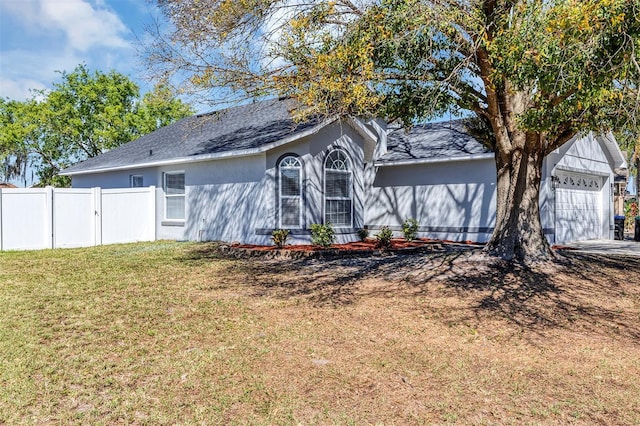 ranch-style home with a garage, driveway, a front yard, and fence