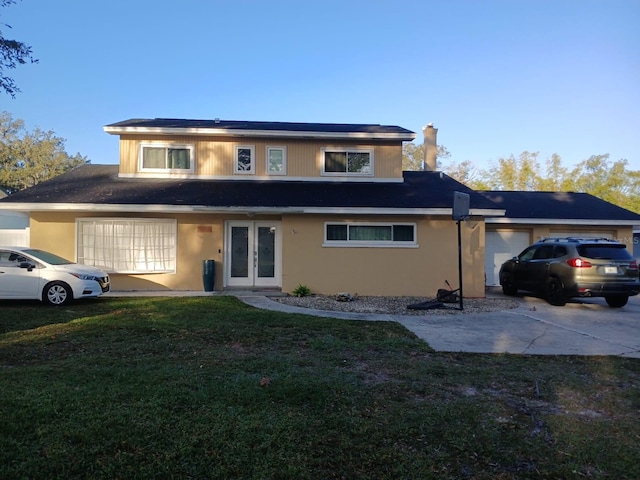 traditional-style house with solar panels, concrete driveway, an attached garage, french doors, and a front yard