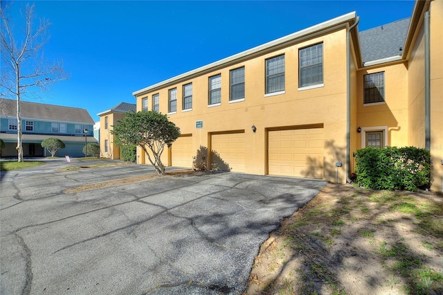 view of property featuring a garage, driveway, and stucco siding