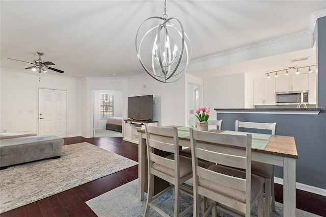 dining room with crown molding, dark wood finished floors, baseboards, and ceiling fan with notable chandelier