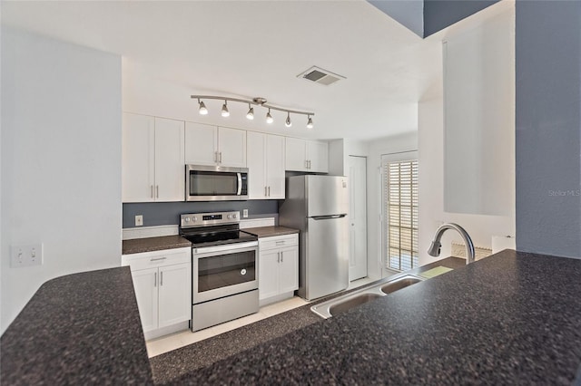 kitchen with appliances with stainless steel finishes, white cabinets, visible vents, and a sink