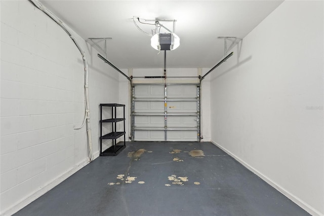 garage with baseboards, concrete block wall, and a garage door opener