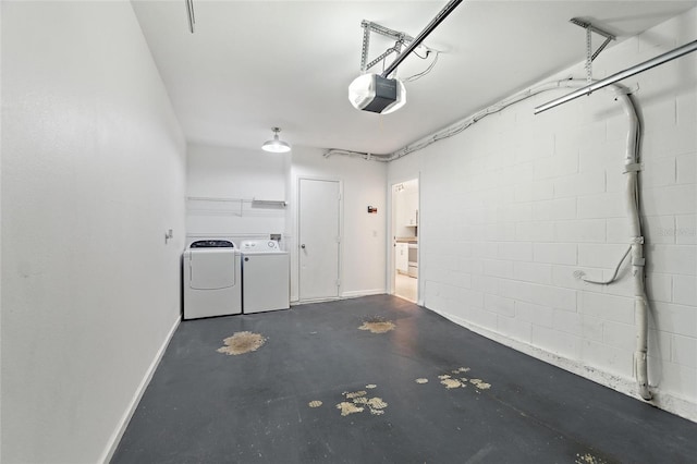 garage featuring a garage door opener, concrete block wall, independent washer and dryer, and baseboards