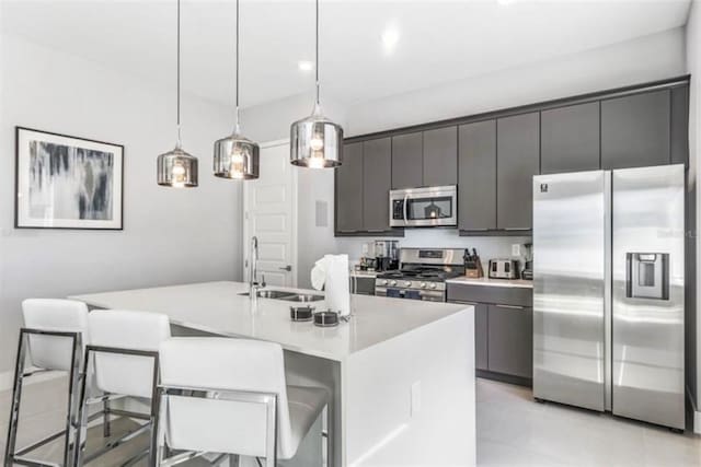 kitchen featuring a center island with sink, light countertops, a kitchen breakfast bar, stainless steel appliances, and a sink