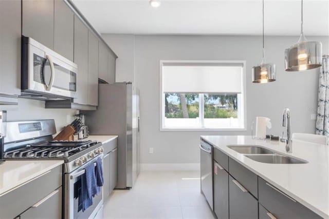 kitchen featuring a sink, light countertops, appliances with stainless steel finishes, and gray cabinetry