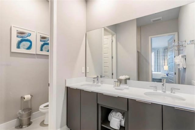 bathroom featuring double vanity, toilet, visible vents, and a sink