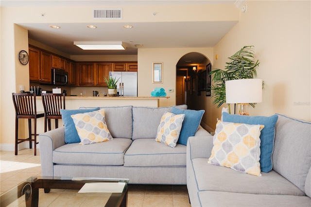 living room with recessed lighting, light tile patterned flooring, arched walkways, and visible vents