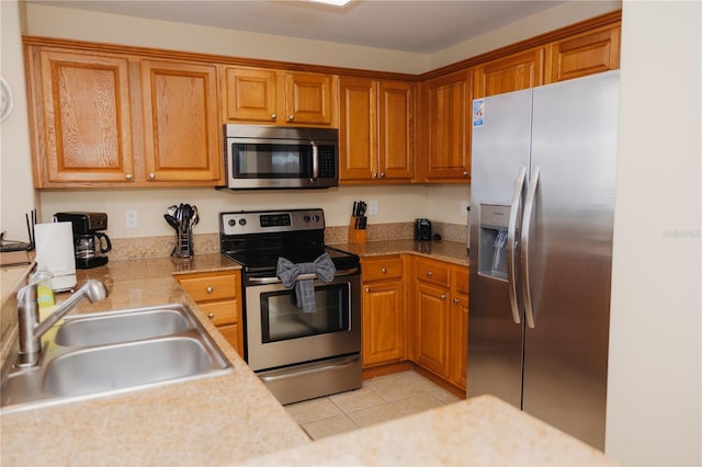 kitchen with light tile patterned flooring, stainless steel appliances, light countertops, and a sink