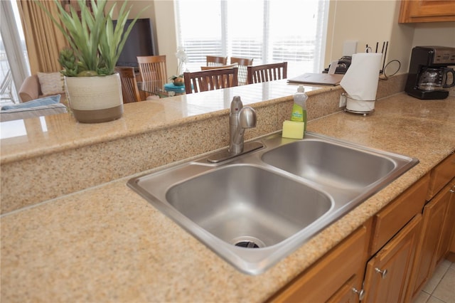 kitchen featuring light tile patterned floors, brown cabinets, light countertops, and a sink