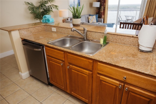 kitchen with light tile patterned floors, a sink, light countertops, and stainless steel dishwasher