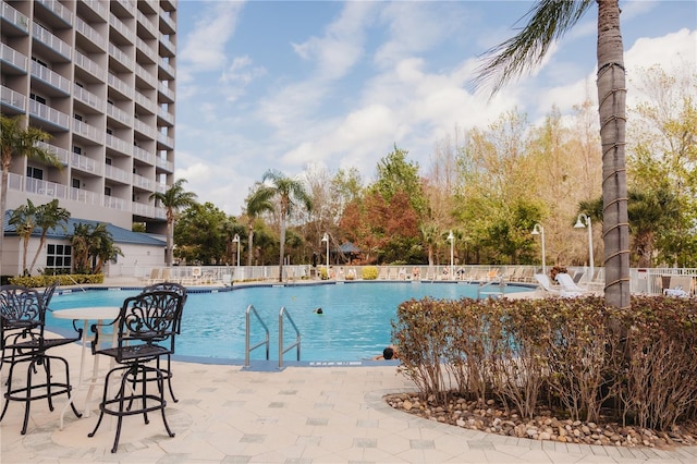 community pool with a patio and fence