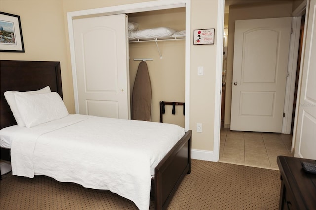 tiled bedroom featuring baseboards and a closet