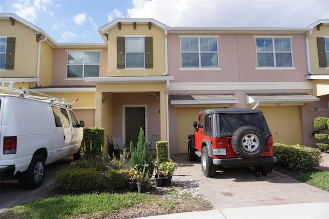 view of property with driveway, an attached garage, and stucco siding