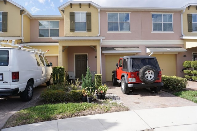 view of property with a garage, driveway, and stucco siding