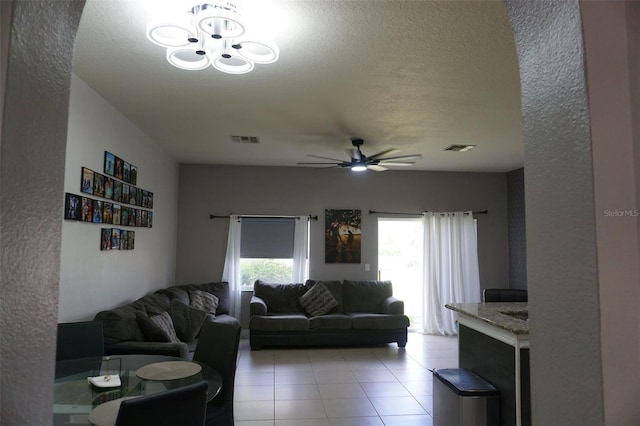 living room featuring visible vents, ceiling fan, and a textured ceiling