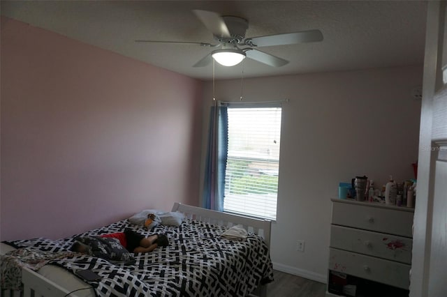 bedroom featuring wood finished floors, a ceiling fan, and baseboards