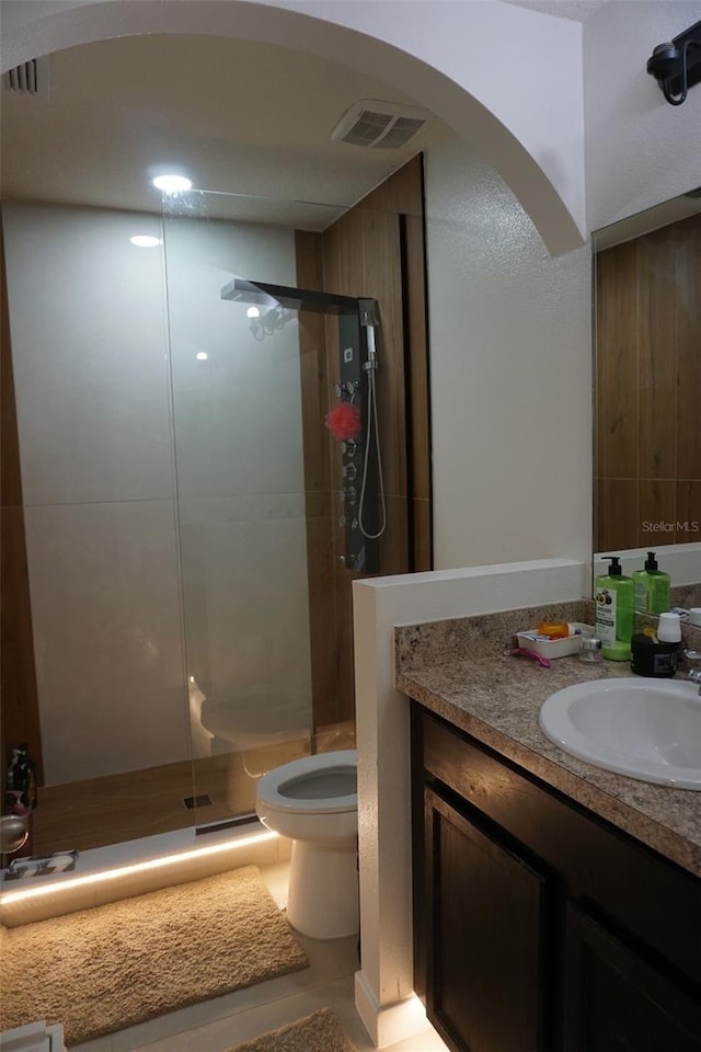 full bath featuring toilet, a stall shower, vanity, and visible vents