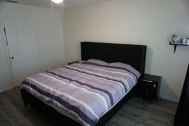 bedroom with baseboards, visible vents, and wood finished floors